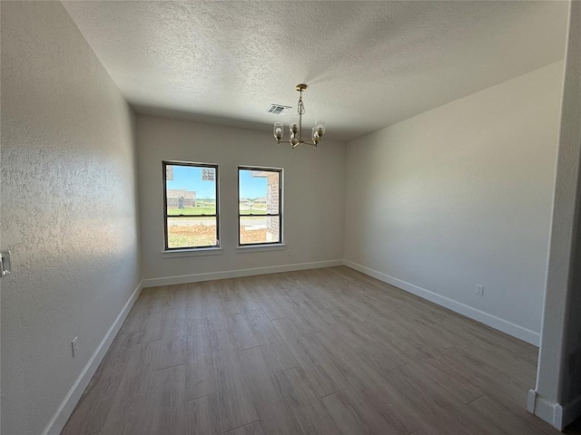 5 Old Glory Ave, Altus, OK 73521 - spare room with a chandelier, wood finished floors, a textured ceiling, and baseboards