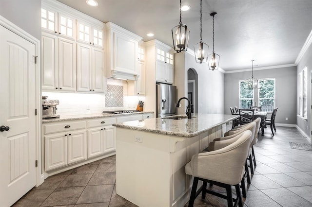 19633 Stratmore Way, Edmond, OK 73012 - kitchen featuring a chandelier, appliances with stainless steel finishes, arched walkways, a kitchen island with sink, and backsplash
