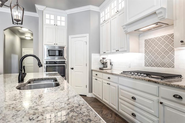 19633 Stratmore Way, Edmond, OK 73012 - kitchen with stainless steel appliances, a sink, arched walkways, crown molding, and custom range hood