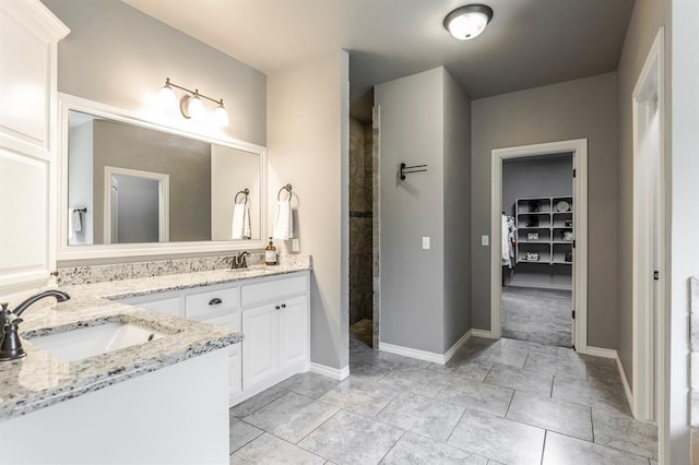19633 Stratmore Way, Edmond, OK 73012 - bathroom featuring double vanity, tiled shower, and baseboards