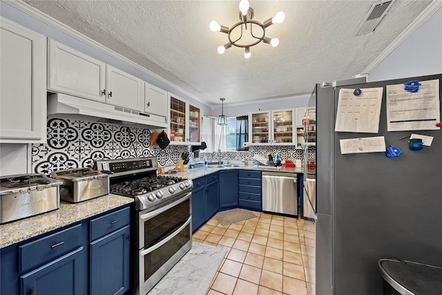 5505 S Villa Ave, Oklahoma City, OK 73119 - kitchen featuring stainless steel appliances, under cabinet range hood, blue cabinetry, a chandelier, and a textured ceiling