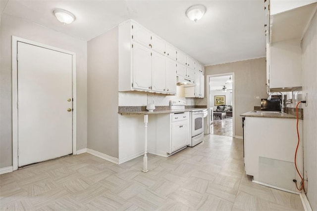 2600 NW 34th St, Oklahoma City, OK 731 - kitchen with white electric stove, under cabinet range hood, a ceiling fan, white cabinetry, and baseboards