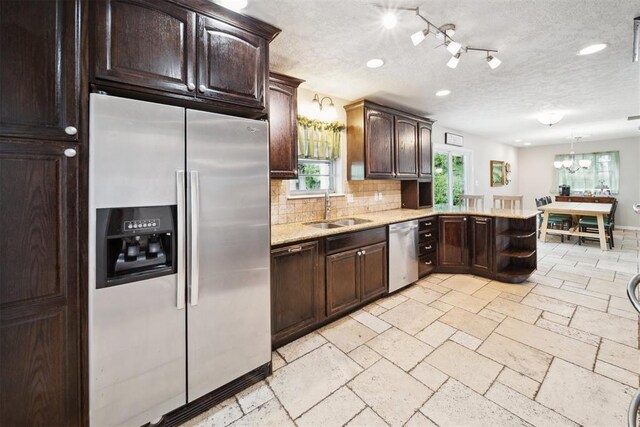 700 Nancy Lynn Ter, Norman, OK 73069 - kitchen with stainless steel appliances, a sink, dark brown cabinets, a textured ceiling, and tasteful backsplash