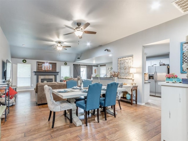 419 NE 23rd Ter, Newcastle, OK 73065 - dining area with ceiling fan, a tile fireplace, light wood-style flooring, and baseboards