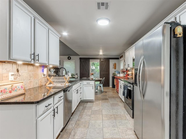 419 NE 23rd Ter, Newcastle, OK 73065 - kitchen with stainless steel appliances, a peninsula, dark countertops, and backsplash