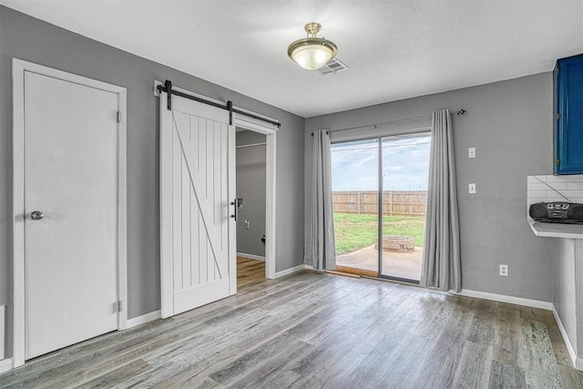 1904 Gemini St, Altus, OK 73521 - unfurnished dining area with a barn door, wood finished floors, and baseboards