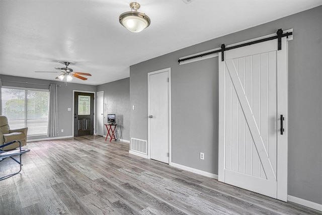1904 Gemini St, Altus, OK 73521 - unfurnished living room featuring a barn door, wood finished floors, ceiling fan, and baseboards