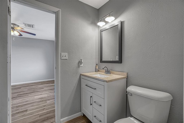 1904 Gemini St, Altus, OK 73521 - bathroom featuring wood finished floors, a ceiling fan, toilet, vanity, and baseboards