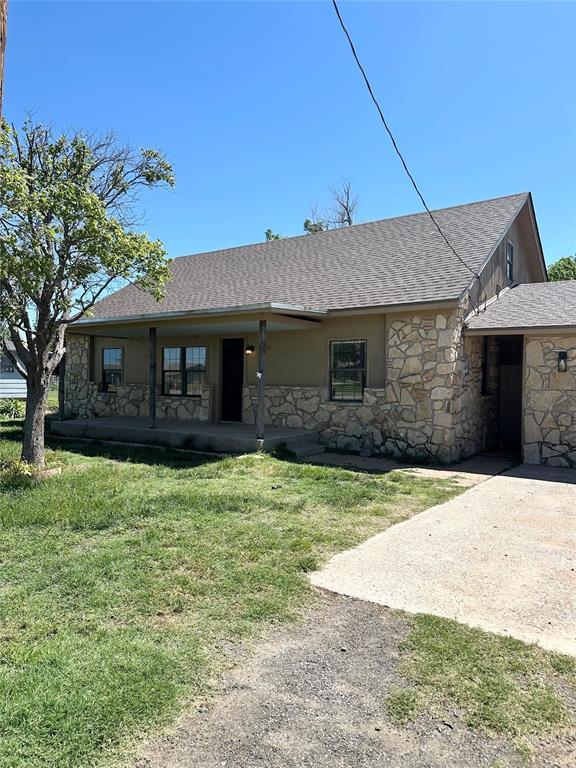 1024 Zinn Ave, Blair, OK 73526 - view of front of property featuring stone siding, a shingled roof, a front yard, and covered porch