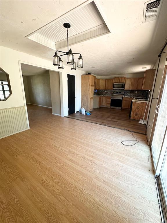 1024 Zinn Ave, Blair, OK 73526 - kitchen with stainless steel appliances, open floor plan, a chandelier, and light wood-style floors