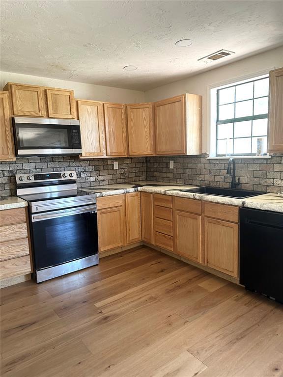 1024 Zinn Ave, Blair, OK 73526 - kitchen with stainless steel appliances, backsplash, a sink, light countertops, and a textured ceiling