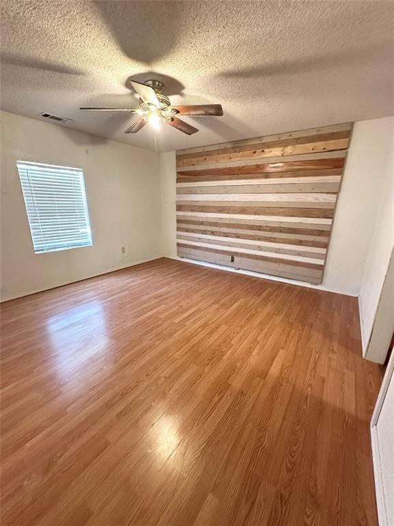 1024 Zinn Ave, Blair, OK 73526 - spare room featuring wood finished floors, ceiling fan, wooden walls, and a textured ceiling