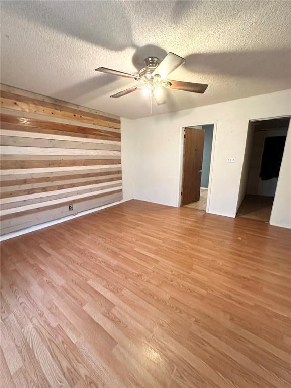 1024 Zinn Ave, Blair, OK 73526 - empty room with light wood-style flooring, ceiling fan, a textured ceiling, and wood walls