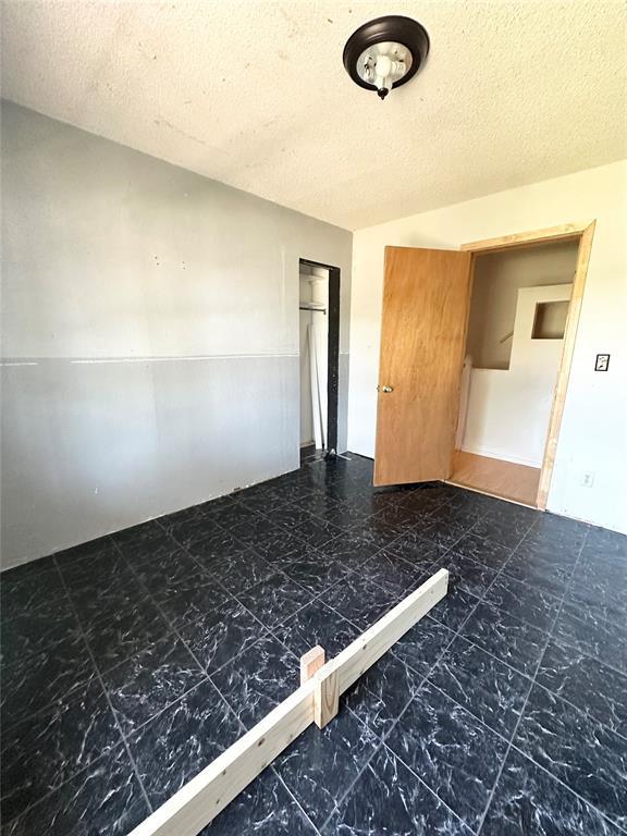 1024 Zinn Ave, Blair, OK 73526 - unfurnished bedroom featuring a textured ceiling and a closet