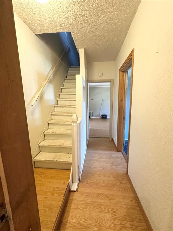 1024 Zinn Ave, Blair, OK 73526 - staircase with a textured ceiling, wood finished floors, and baseboards