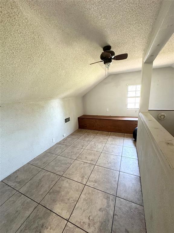 1024 Zinn Ave, Blair, OK 73526 - additional living space with a textured ceiling, lofted ceiling, a ceiling fan, and light tile patterned floors
