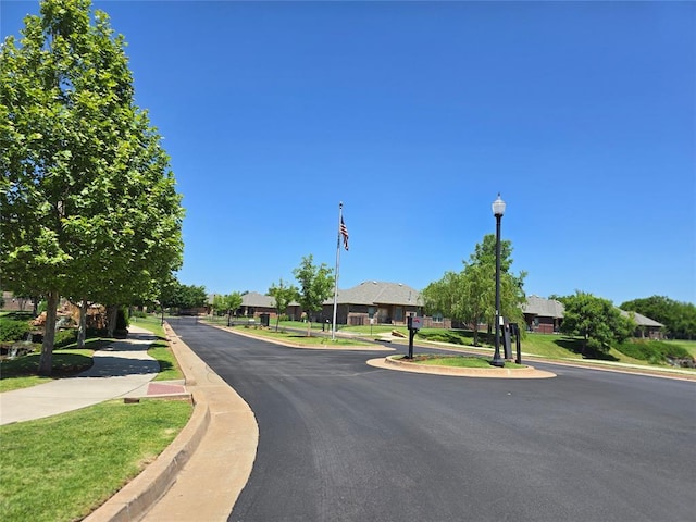 5608 NW 127th St, Oklahoma City, OK 73142 - view of asphalt road featuring curbs, sidewalks, street lighting, and a residential view