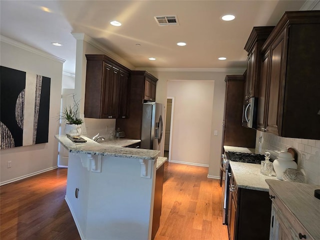 5608 NW 127th St, Oklahoma City, OK 73142 - kitchen featuring stainless steel appliances, a breakfast bar, backsplash, light stone counters, and ornamental molding