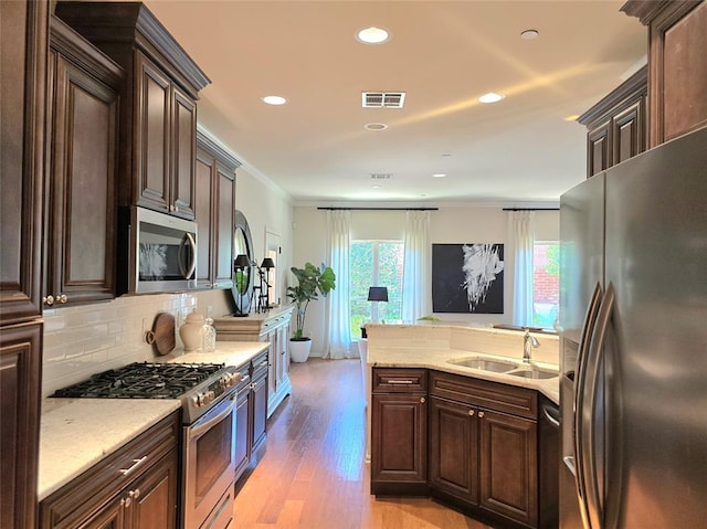 5608 NW 127th St, Oklahoma City, OK 73142 - kitchen with stainless steel appliances, a sink, light wood-style floors, backsplash, and dark brown cabinetry