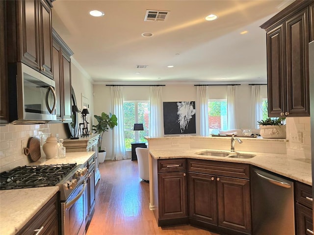 5608 NW 127th St, Oklahoma City, OK 73142 - kitchen featuring stainless steel appliances, a sink, light wood-style floors, dark brown cabinets, and a peninsula