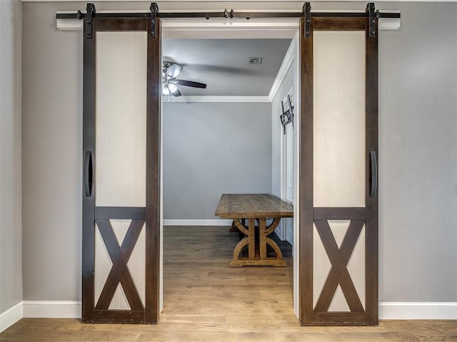 832 Gateway Bridge Rd, Edmond, OK 73034 - hallway with a barn door, wood finished floors, baseboards, and crown molding