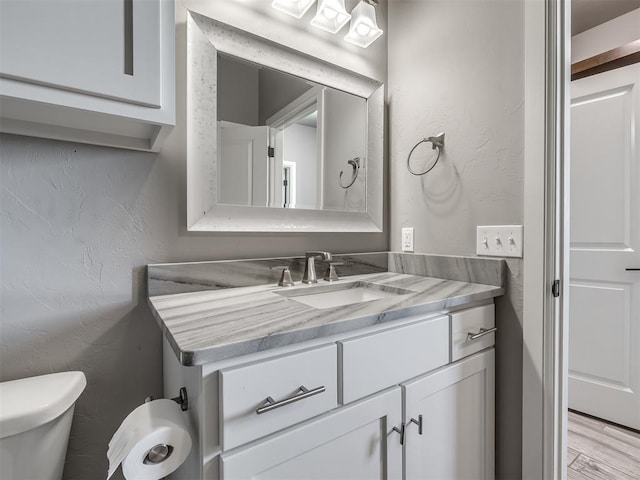 832 Gateway Bridge Rd, Edmond, OK 73034 - bathroom with vanity, toilet, wood finished floors, and a textured wall