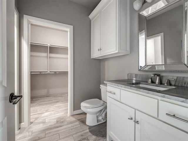 832 Gateway Bridge Rd, Edmond, OK 73034 - bathroom with wood finished floors, vanity, toilet, baseboards, and a spacious closet