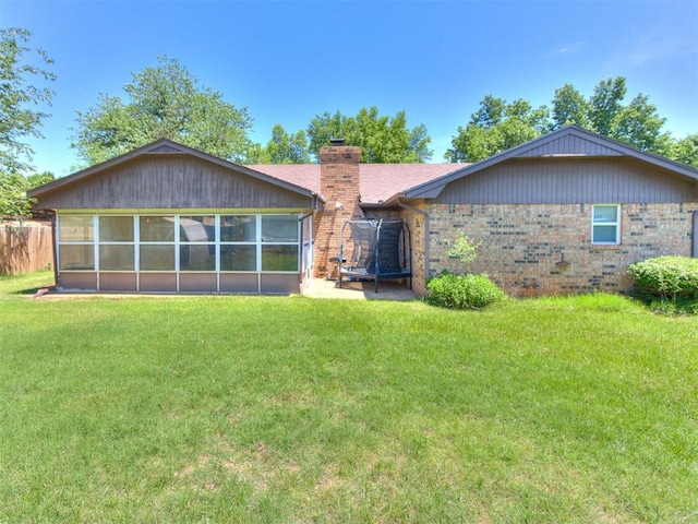 back of house with a chimney, a sunroom, a yard, and brick siding