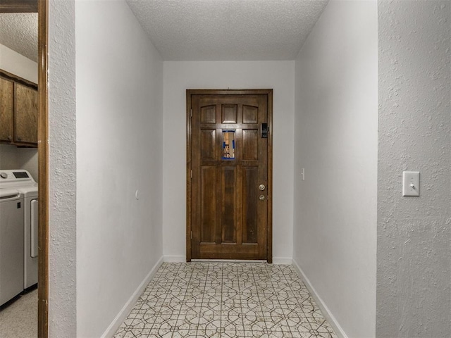 entryway with separate washer and dryer, a textured ceiling, and baseboards