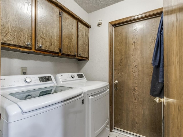 laundry room featuring separate washer and dryer, cabinet space, and a textured ceiling