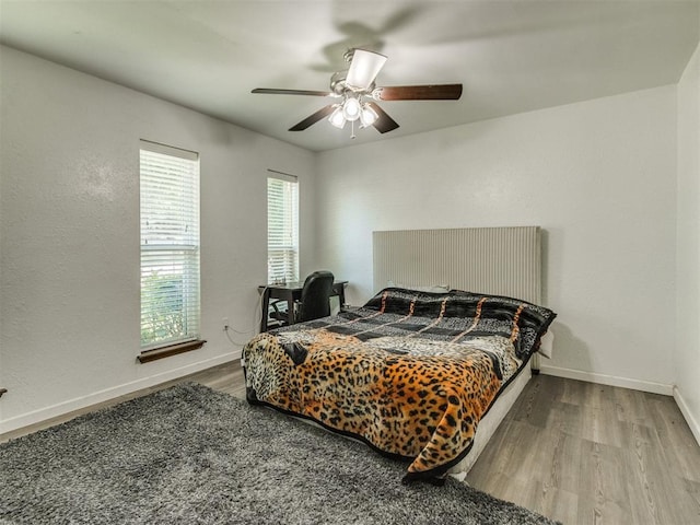 bedroom featuring wood finished floors, baseboards, and ceiling fan