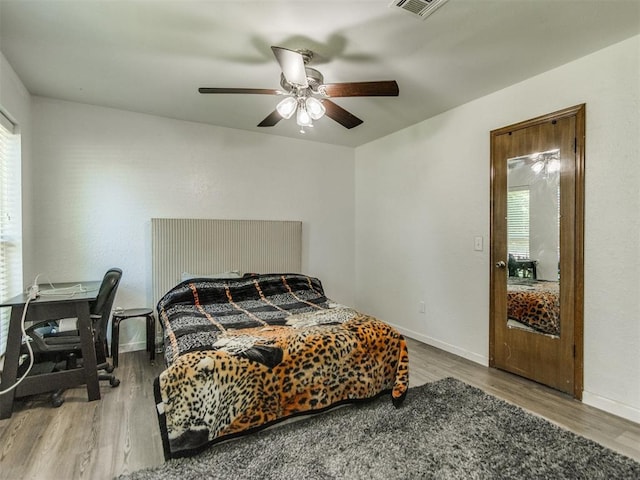 bedroom with multiple windows, wood finished floors, and baseboards