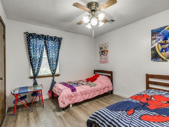 bedroom featuring a textured ceiling, wood finished floors, baseboards, and ceiling fan