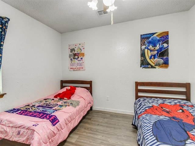 bedroom featuring wood finished floors, a textured ceiling, and baseboards