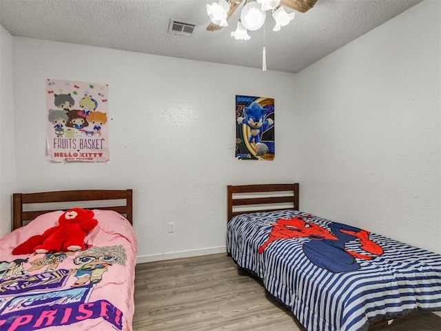 bedroom with wood finished floors, baseboards, a ceiling fan, and a textured ceiling