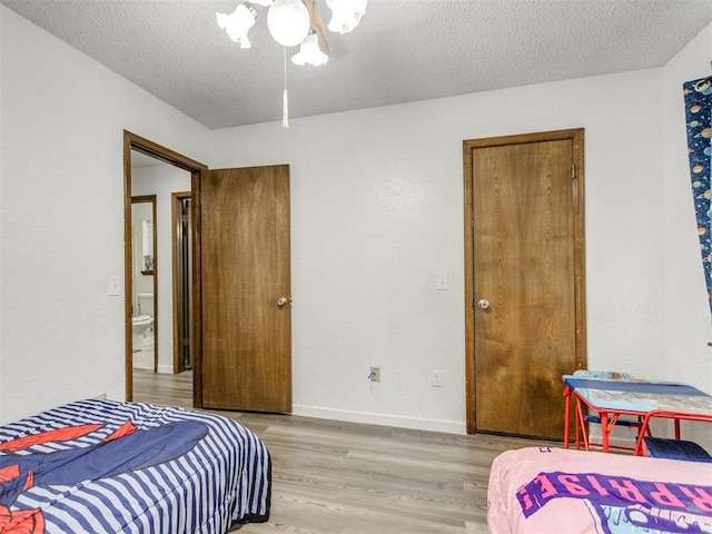 bedroom featuring a textured ceiling, light wood-style floors, and baseboards