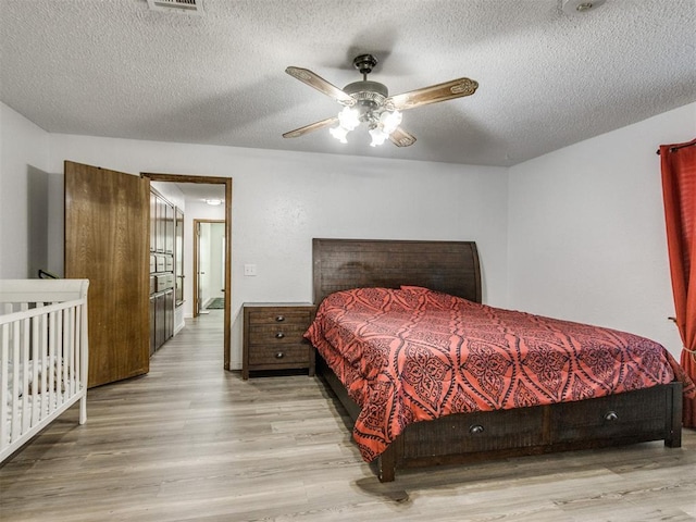 bedroom with wood finished floors, a textured ceiling, and ceiling fan