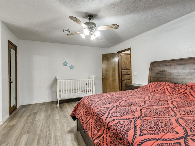 bedroom with wood finished floors, a textured ceiling, and a ceiling fan