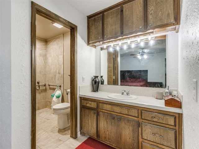 full bathroom featuring toilet, a ceiling fan, a textured wall, vanity, and tile patterned flooring