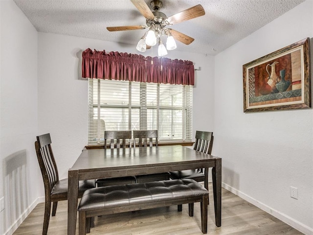 dining area featuring a textured ceiling, wood finished floors, a ceiling fan, and baseboards