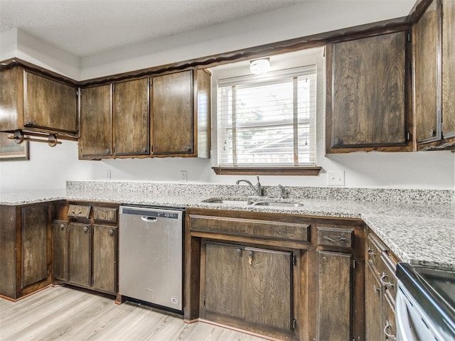 kitchen with stainless steel appliances, a sink, light wood-style floors, dark brown cabinets, and light stone countertops