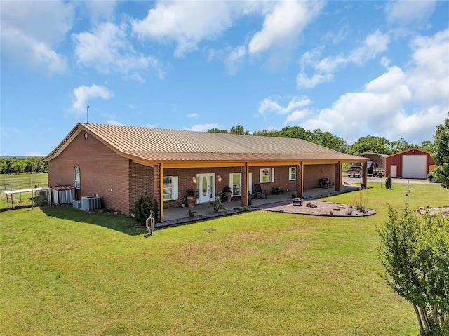 28256 N County Road 3210th Rd, Wynnewood, OK 73098 - back of property featuring brick siding, a patio, a detached garage, central AC unit, and metal roof
