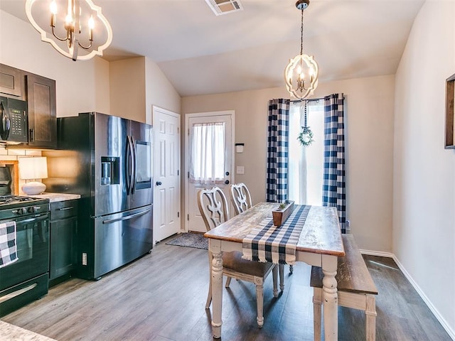 11704 NW 99th Ter, Yukon, OK 73099 - dining area with a chandelier, light wood-style floors, vaulted ceiling, and baseboards