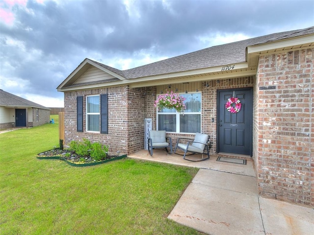 11704 NW 99th Ter, Yukon, OK 73099 - property entrance with brick siding, a yard, and roof with shingles