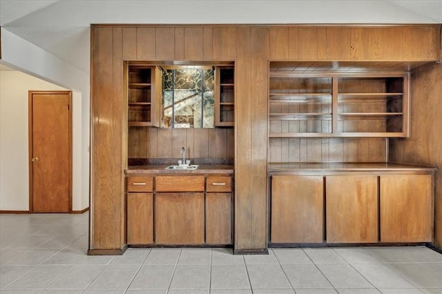 708 Cross Timbers Dr, Moore, OK 73160 - kitchen featuring a sink, open shelves, brown cabinets, light tile patterned floors, and wood walls