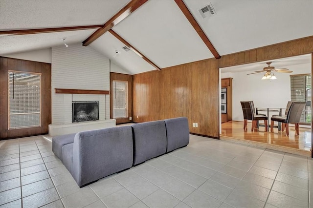 708 Cross Timbers Dr, Moore, OK 73160 - living room with wood walls, light tile patterned flooring, a ceiling fan, a brick fireplace, and plenty of natural light