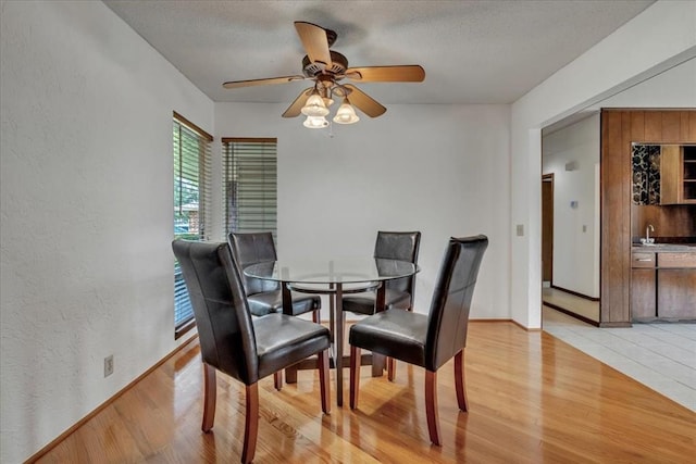 708 Cross Timbers Dr, Moore, OK 73160 - dining area with light wood-style floors, a textured wall, ceiling fan, baseboards, and a textured ceiling