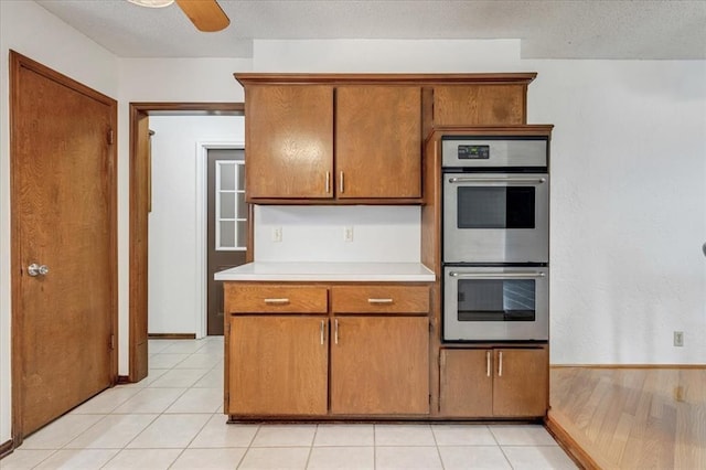 708 Cross Timbers Dr, Moore, OK 73160 - kitchen with double oven, brown cabinets, light countertops, ceiling fan, and a textured ceiling