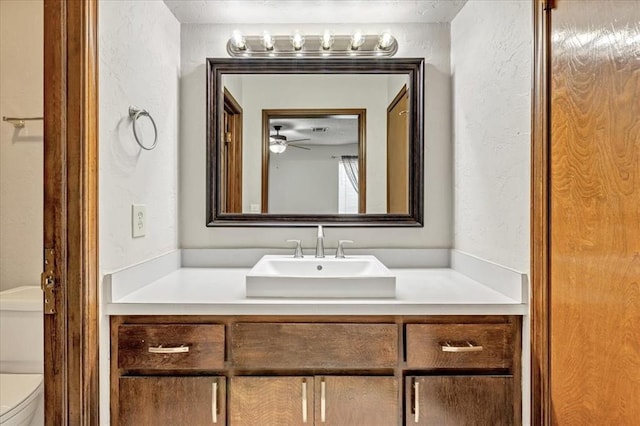 708 Cross Timbers Dr, Moore, OK 73160 - bathroom with vanity, a textured wall, toilet, and a ceiling fan
