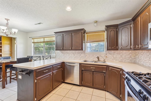 316 SE 6th St, Moore, OK 73160 - kitchen featuring dishwasher, a sink, a textured ceiling, a chandelier, and a peninsula